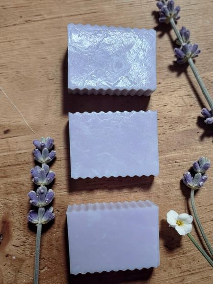 La Neve Soap and Beauty Care lavender botanical bar soaps with fluted edges on a rustic wooden surface with flowers