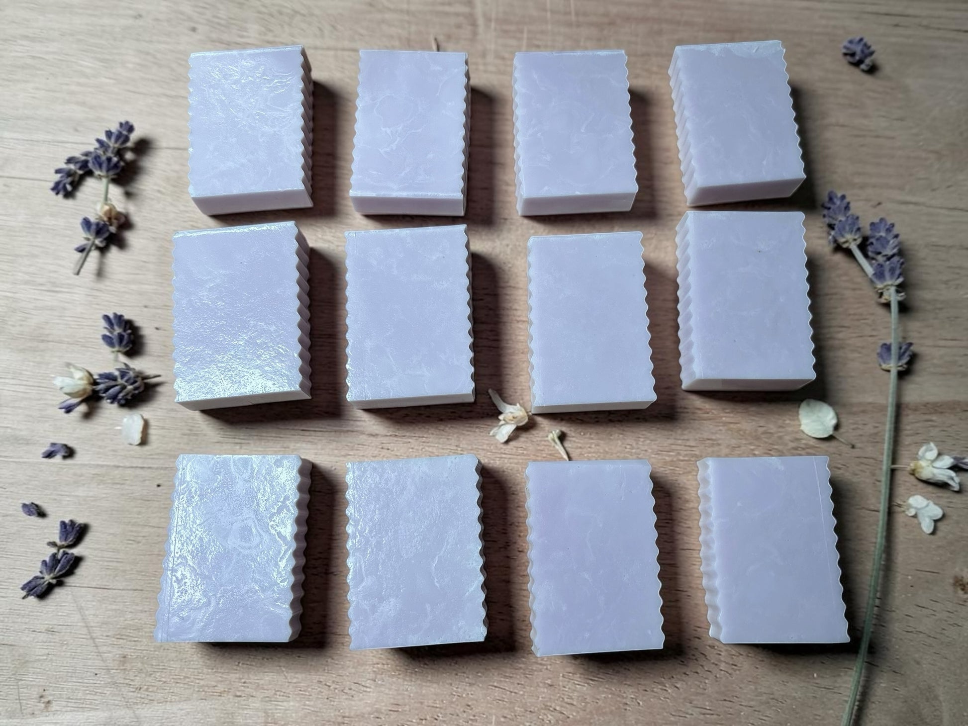 La Neve Soap and Beauty Care lavender botanical bar soaps with fluted edges arranged on a wooden surface with lavender sprigs