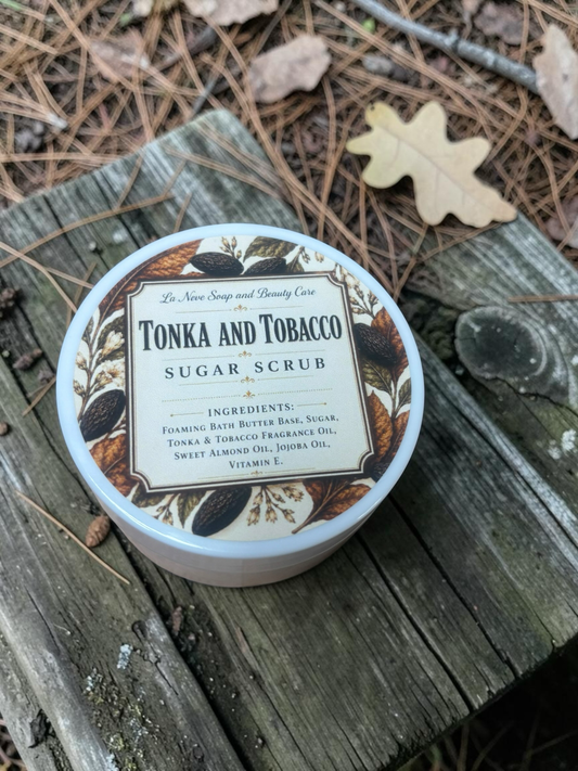 La Neve Soap and Beauty Care Tonka and Tobacco sugar scrub in a white jar, placed on a rustic wooden surface.